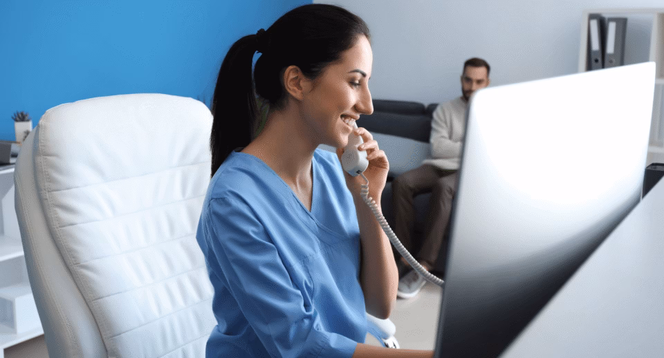 A smiling office manager on the phone sitting at her computer