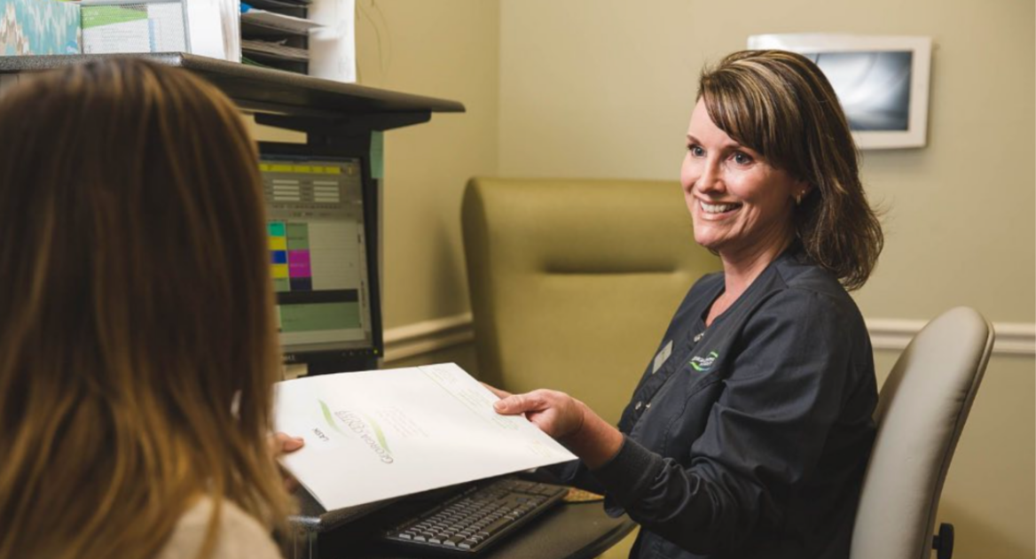 An office administrator hands a team member a clipboard