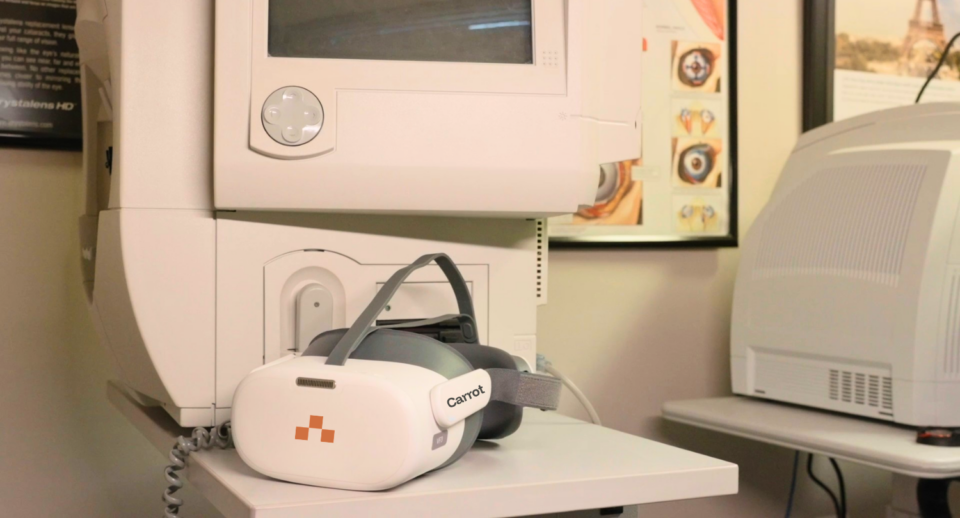 A Carrot headset sits on a table in front of a Humphrey Visual Field Analyzer