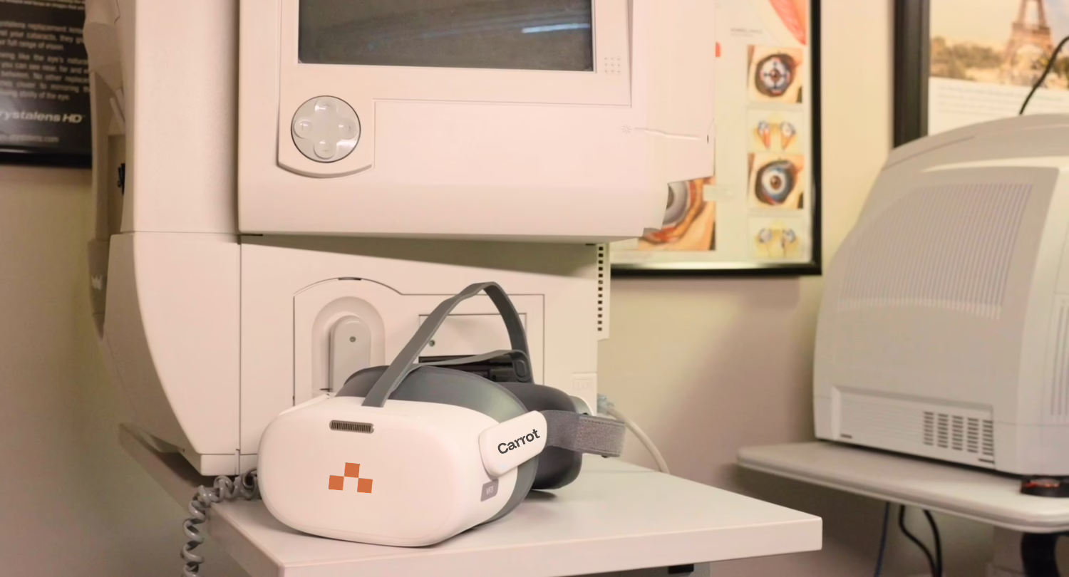 A Carrot headset sits on a table in front of a Humphrey Visual Field Analyzer